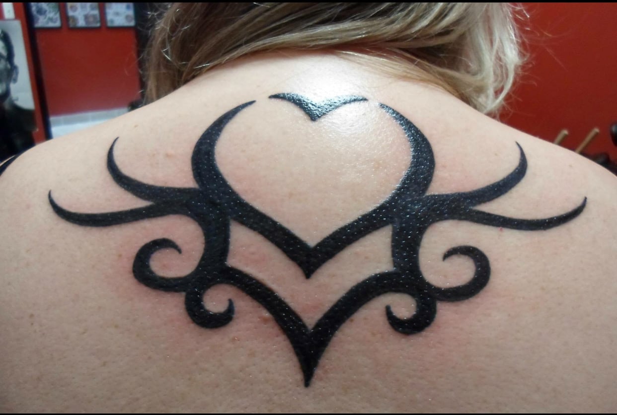 Solid black tribal heart with sweeping symmetrical points, centred across the upper back